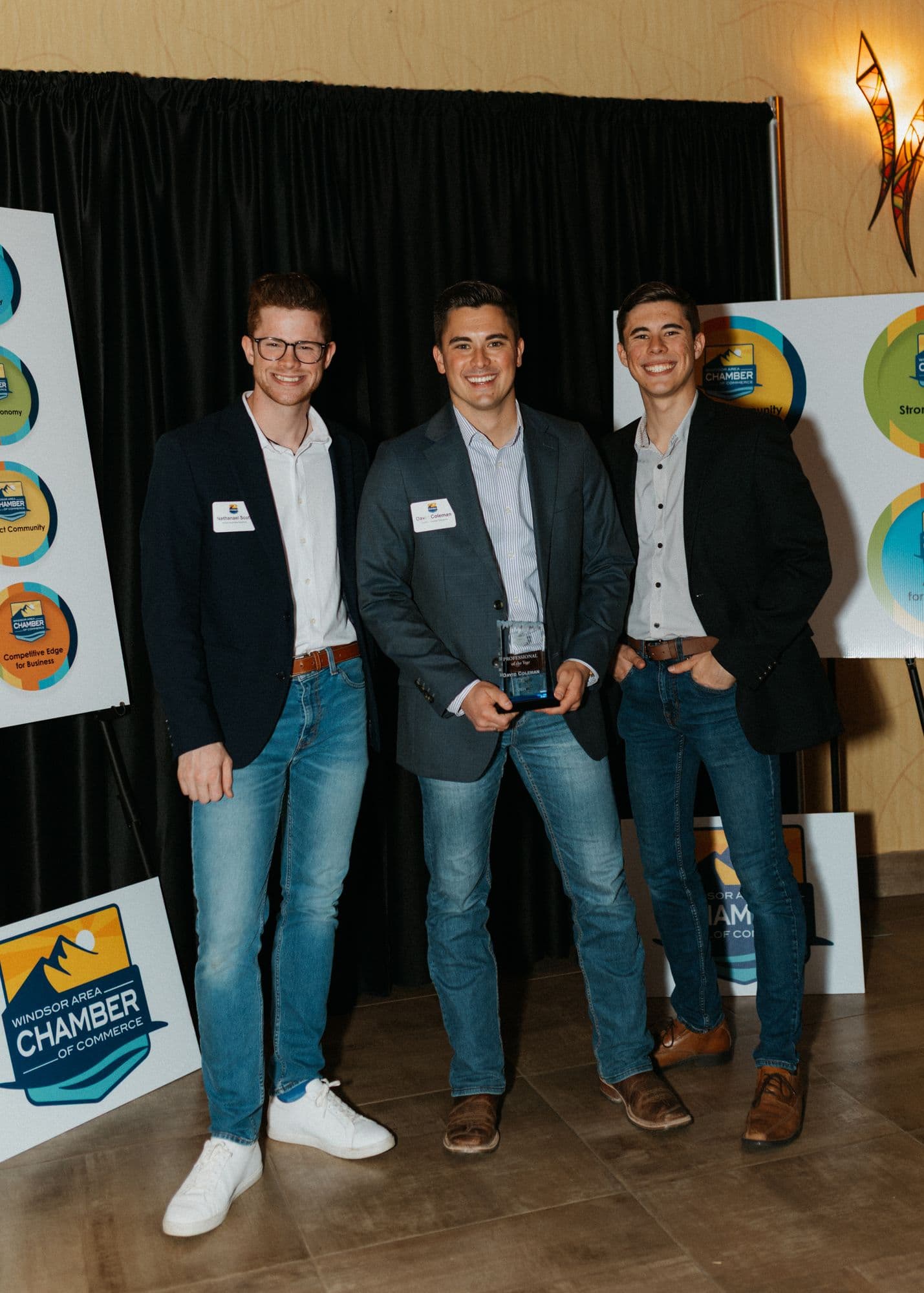 David and two teammates holding an award at a chamber of commerce event