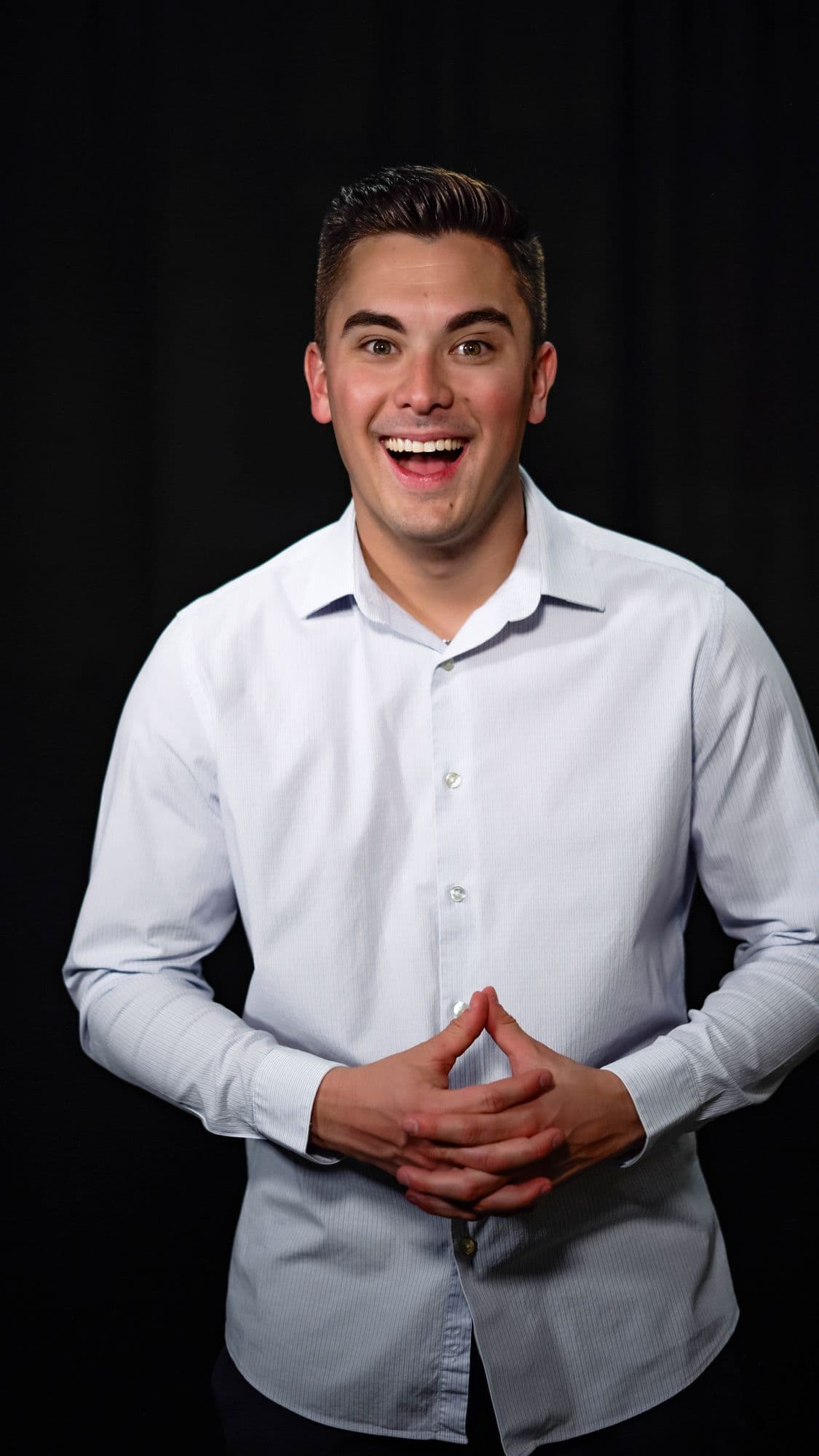 David laughing in a light shirt against a black backdrop